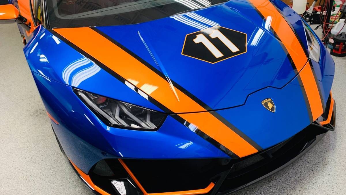A blue and orange sports car with the number 11 on the hood is parked in a garage.