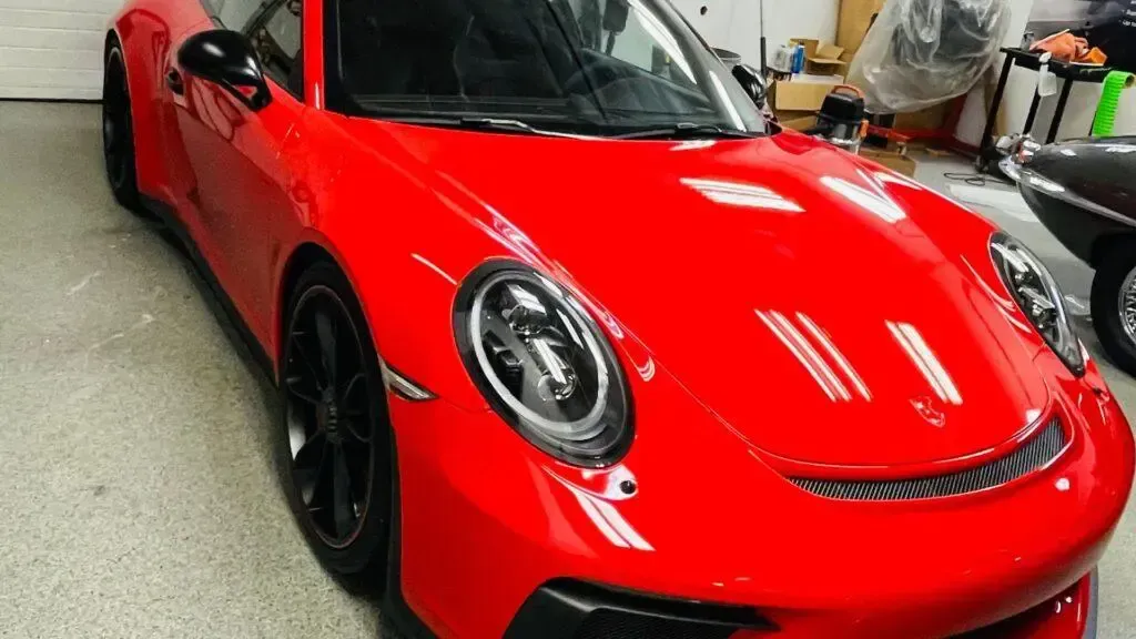 A red porsche 911 is parked in a garage.