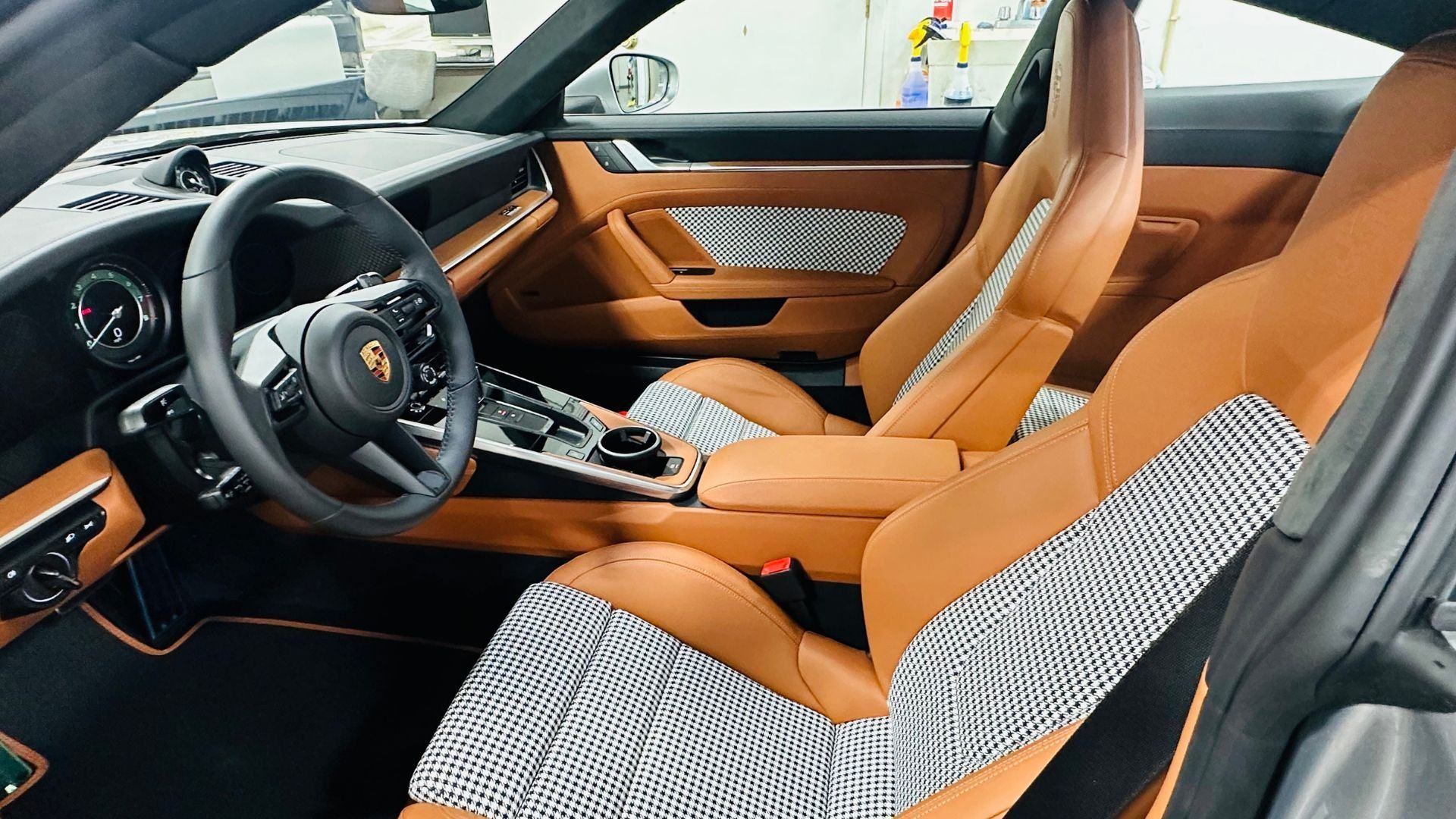 The interior of a porsche 911 turbo s with brown leather seats and a steering wheel.