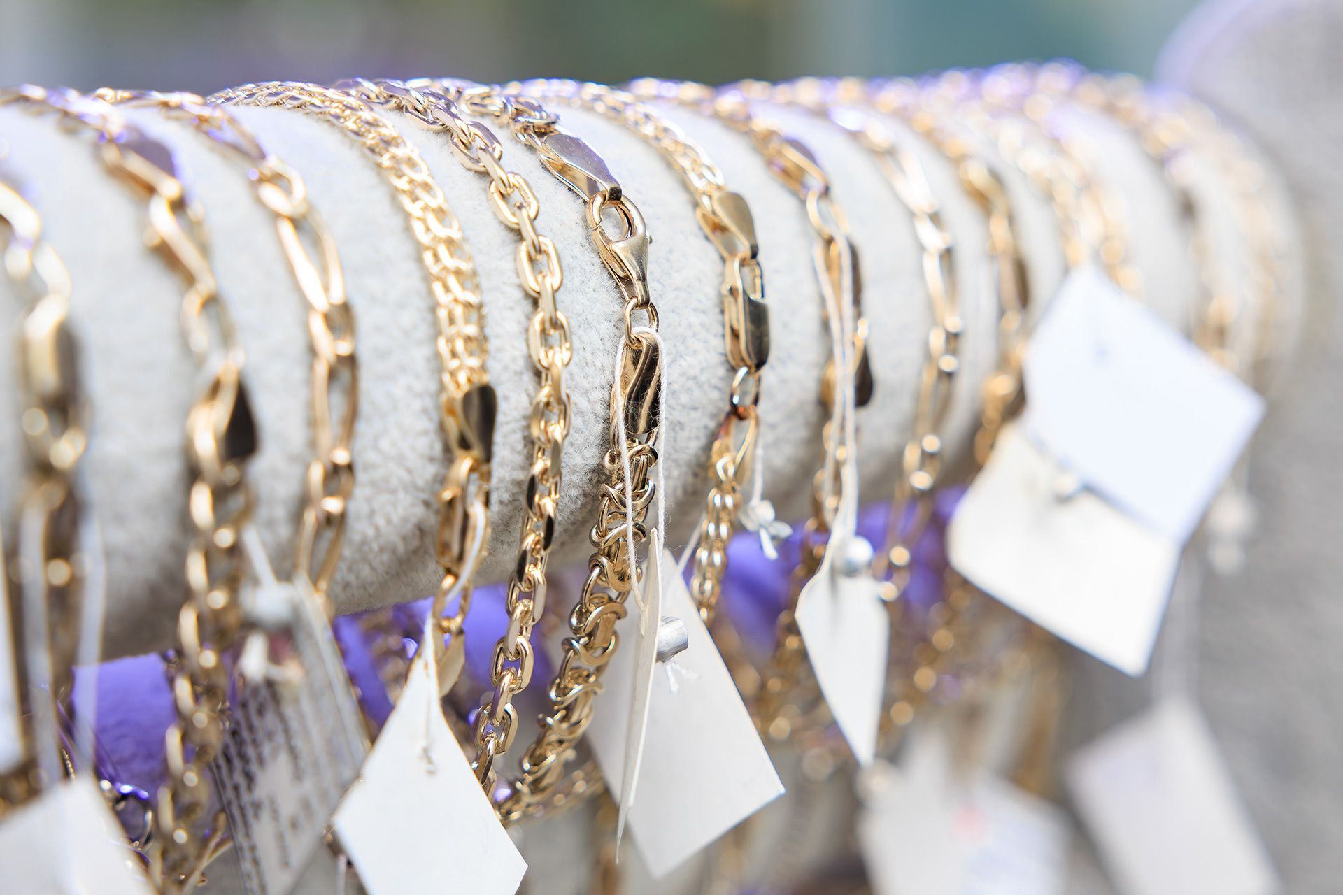 Rows of gold bracelets with white price tags displayed on velvet stands