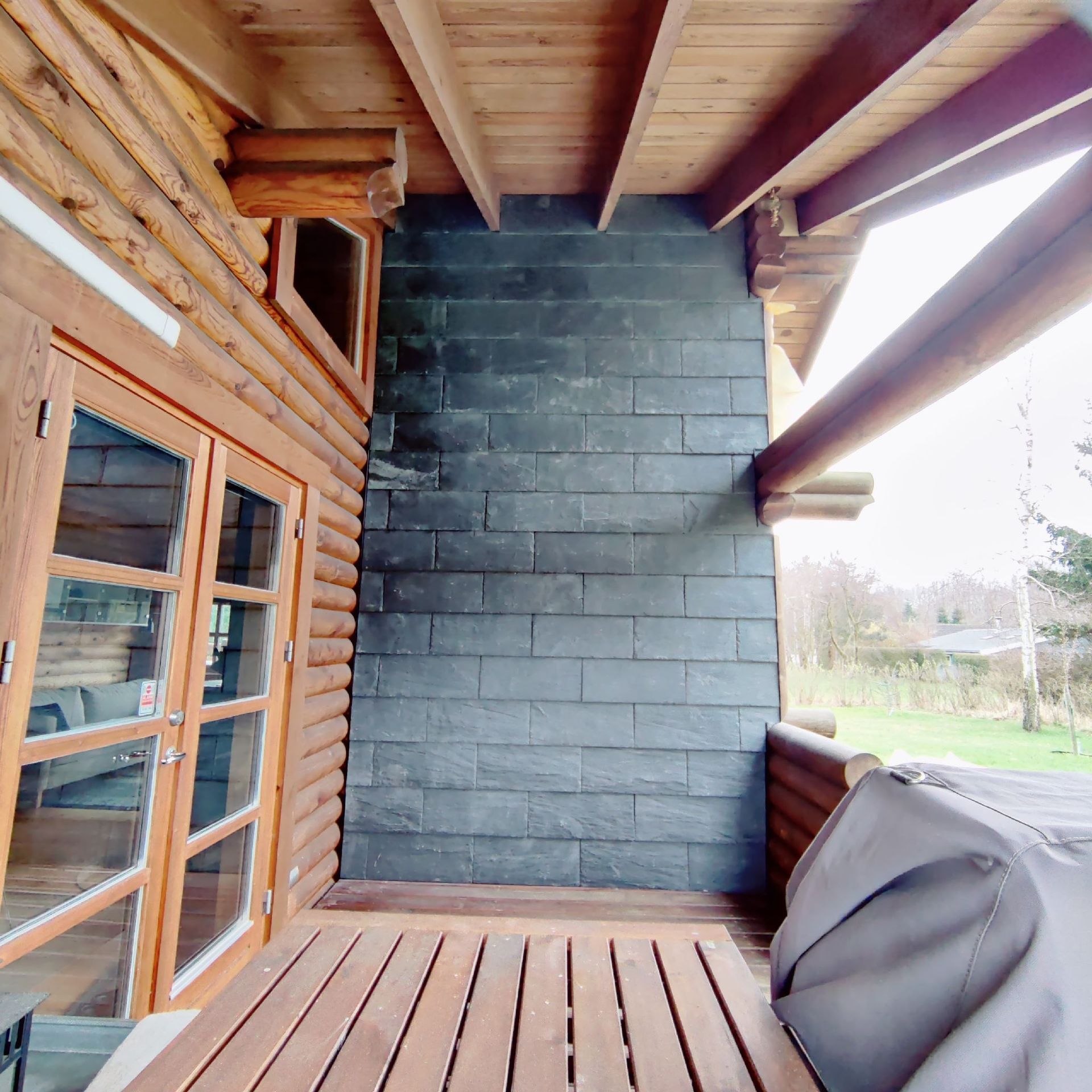 En træveranda med en murstensvæg bagved
