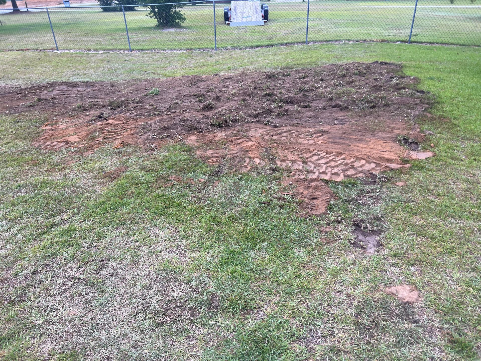 There is a large pile of dirt in the middle of the grass.