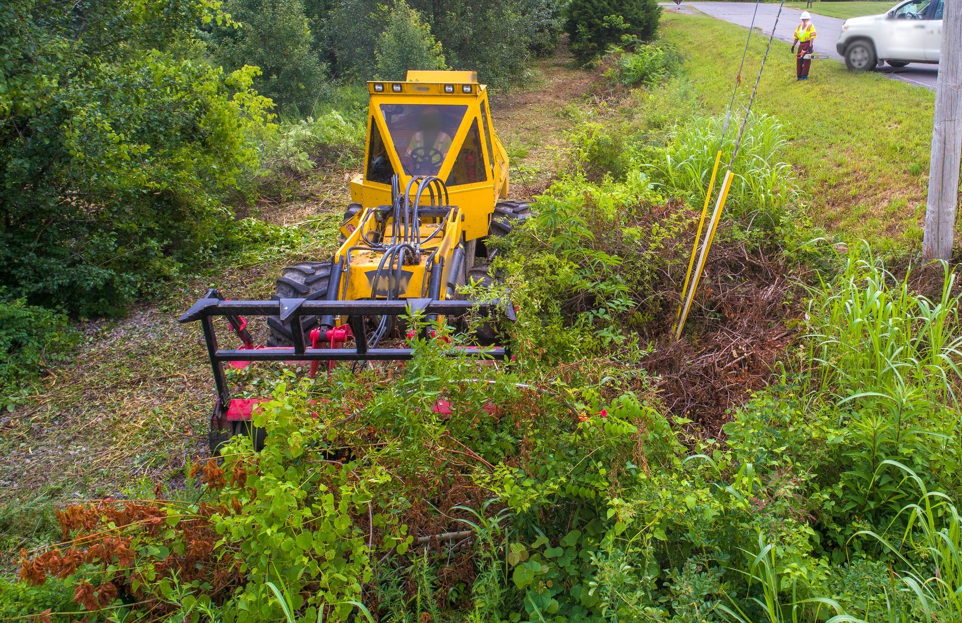 A yellow tractor is sitting in the middle of a lush green field.