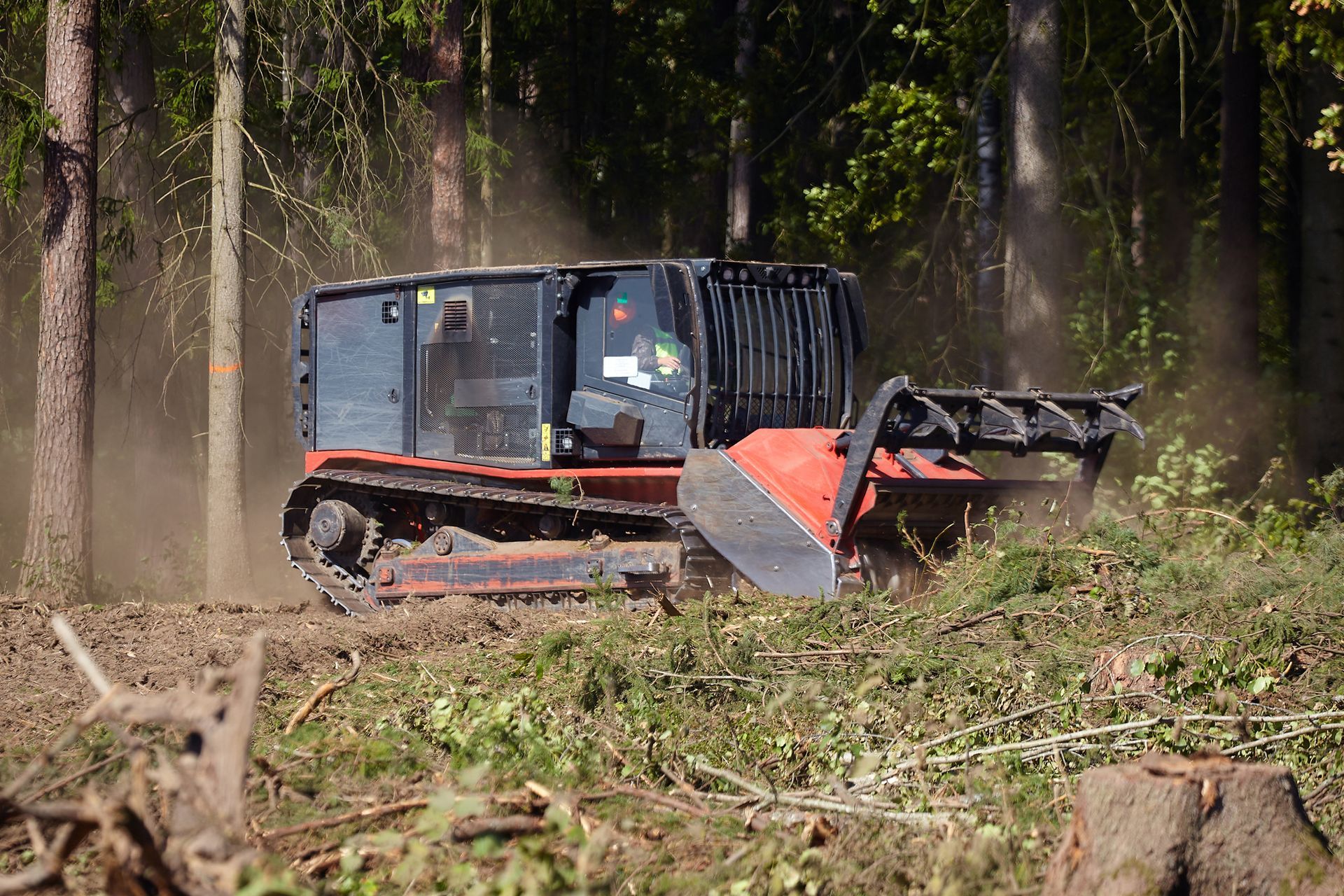 A bulldozer is cutting down trees in the woods.