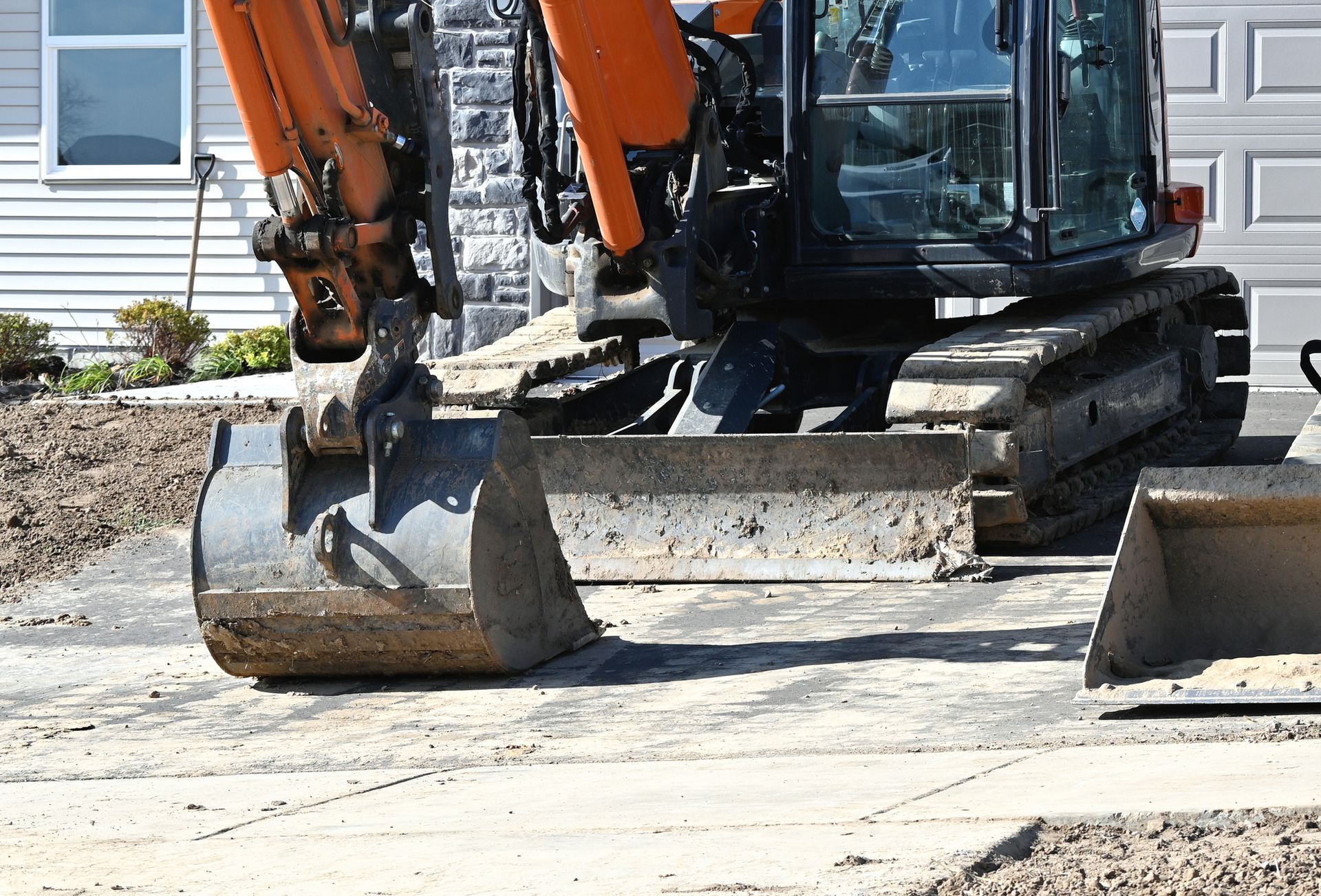 A large excavator is parked in front of a house.