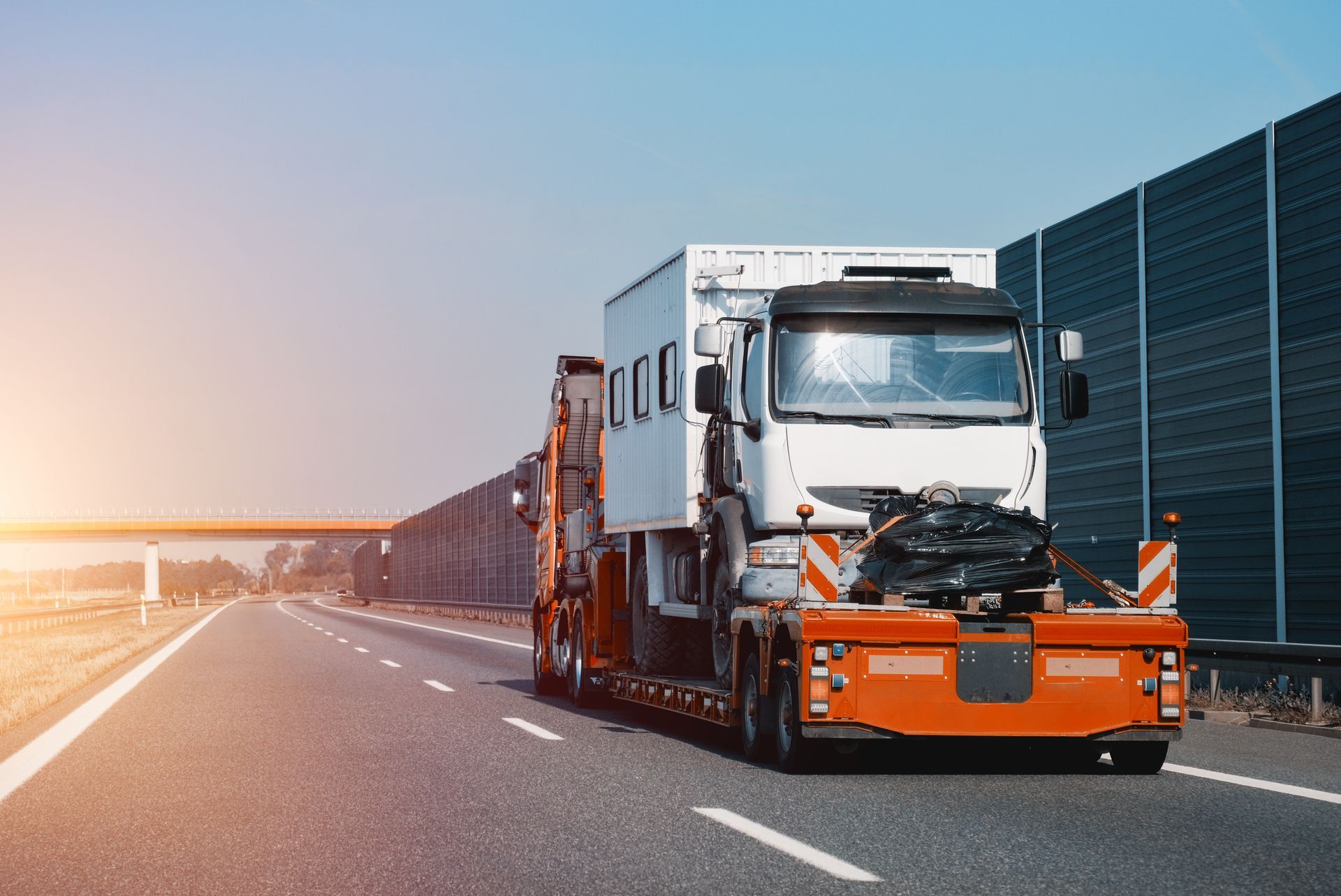 Emergency heavy towing services transporting a disabled truck on the highway.