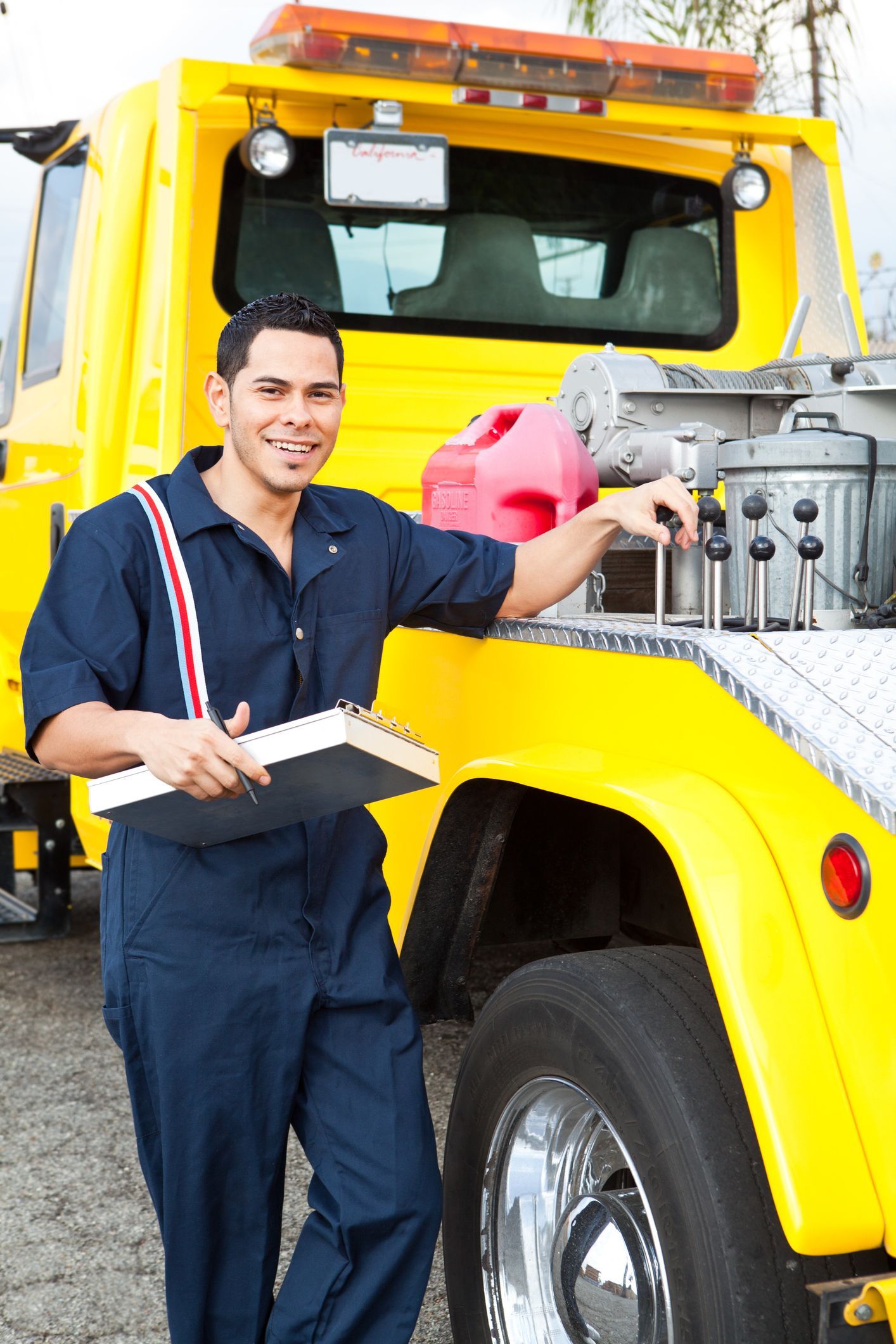 A tow truck driver standing ready to serve beside the tow truck.