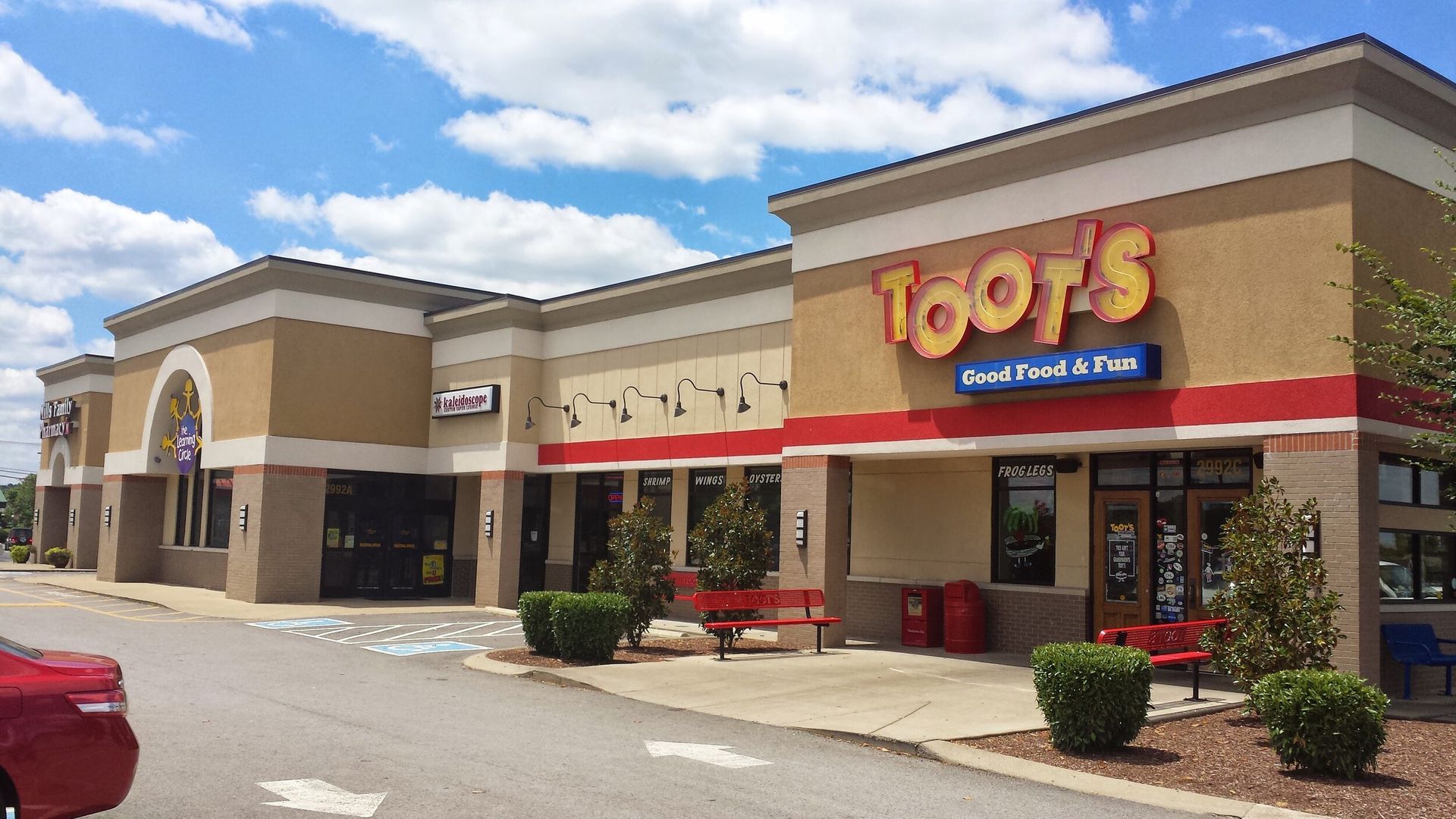 A red car is parked in front of a tootsie 's store