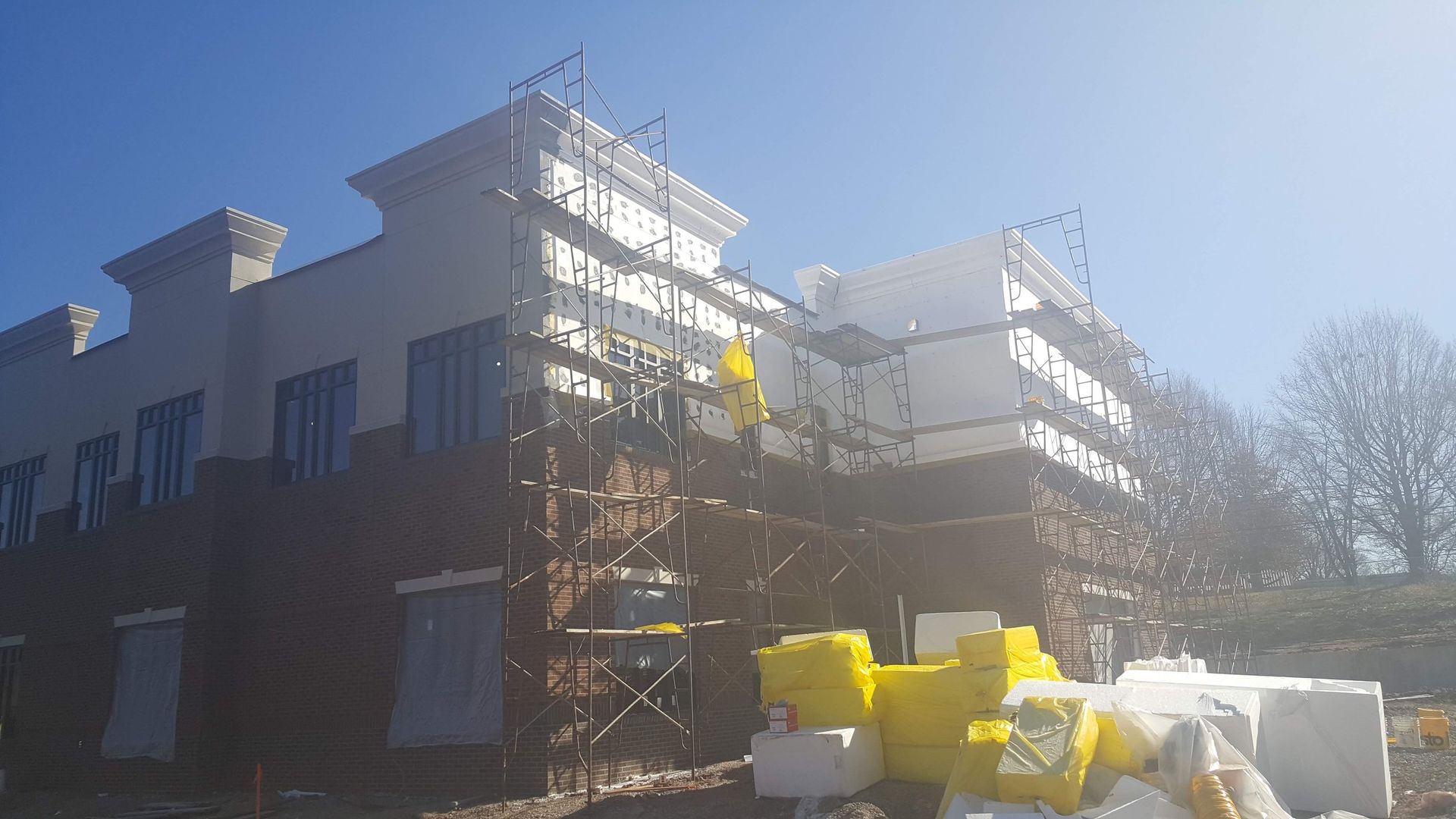 A large building under construction with scaffolding around it and a blue sky in the background.