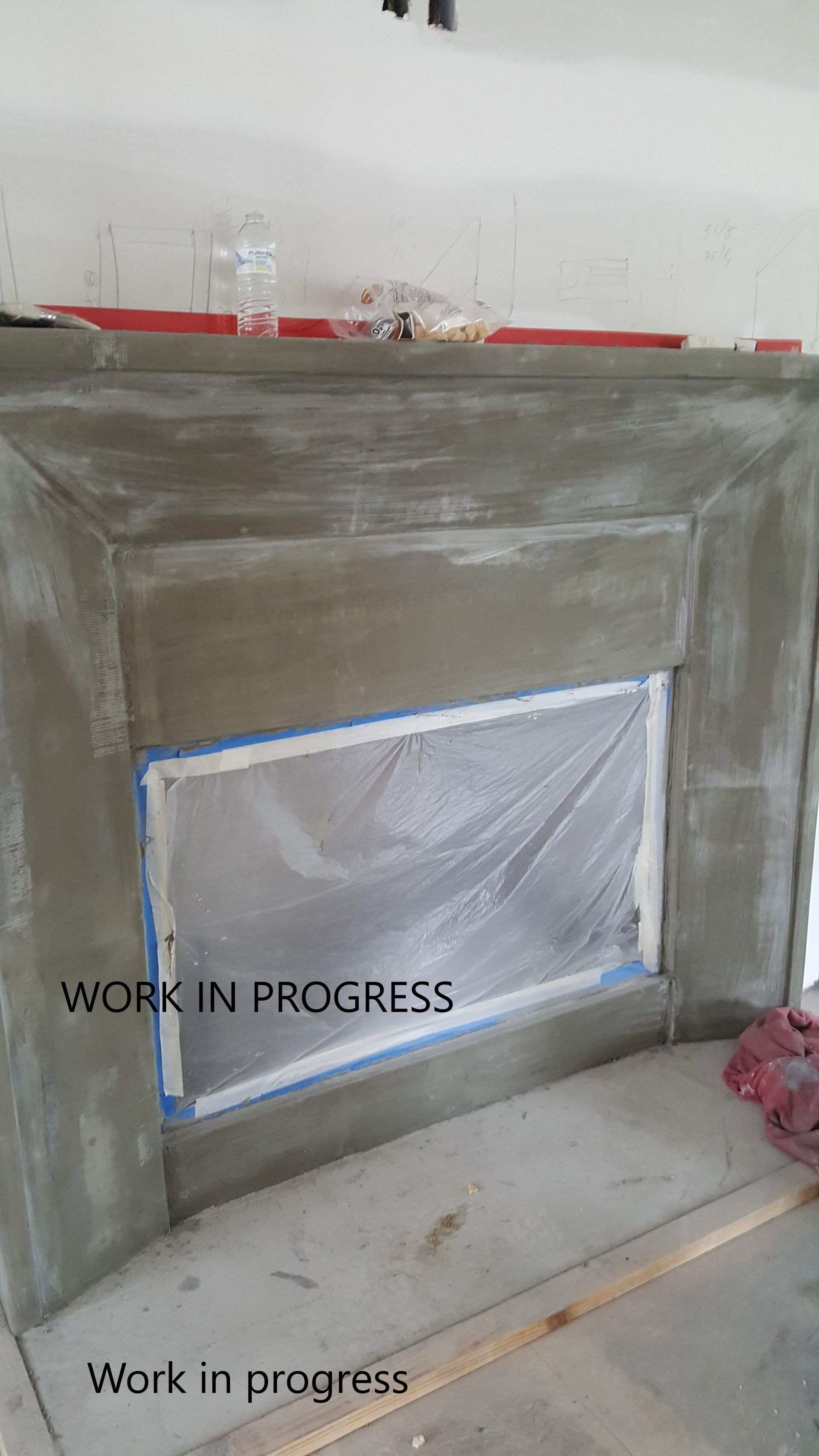A concrete fireplace is being built in a living room.