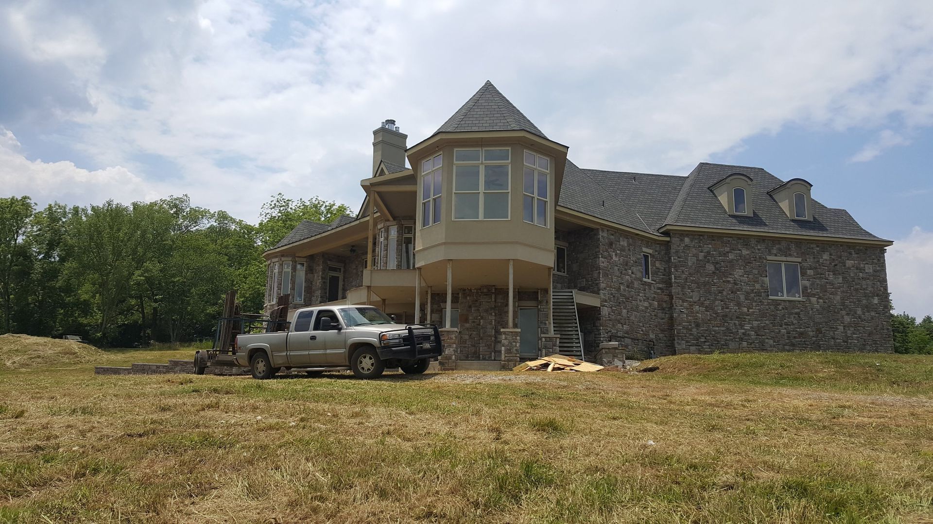 A truck is parked in front of a large stone house.
