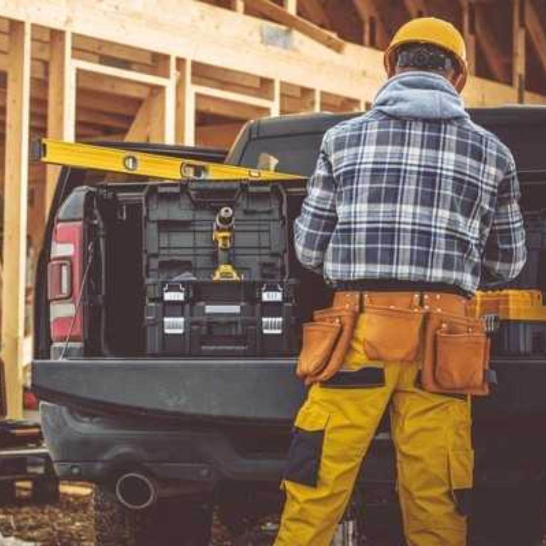 A man is standing next to a truck with tools in the back.