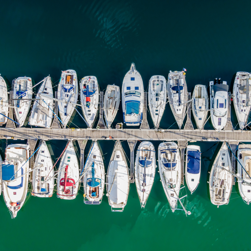A row of boats are docked on a dock in the water.