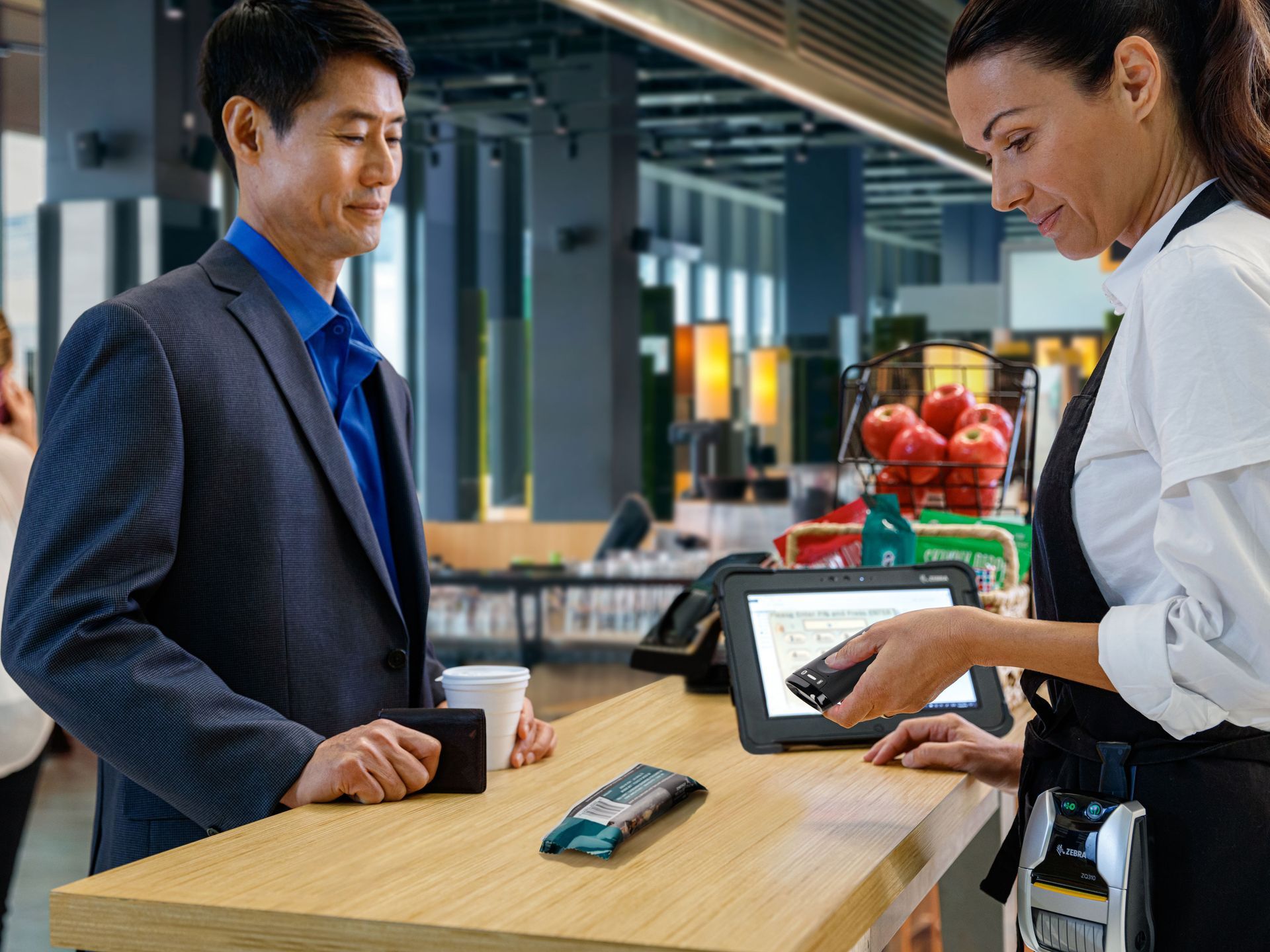 A man in a suit is standing at a counter talking to a waitress.