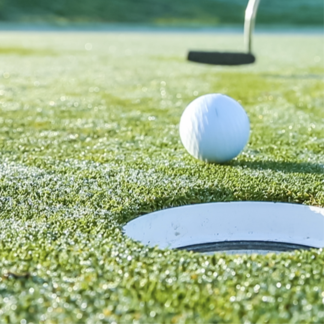 A golf ball is going into a hole on a golf course.