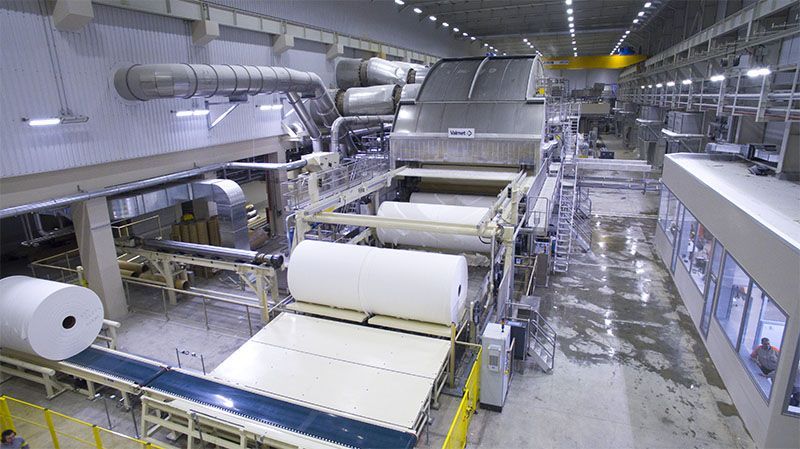 A large factory filled with lots of rolls of paper and machinery.