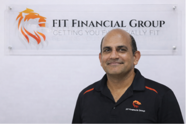 Man smiles below a sign for FIT Financial Group with a lion logo — Fit Financial Group in Leumeah, NSW