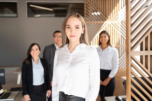 A woman is standing in front of a group of people in an office.