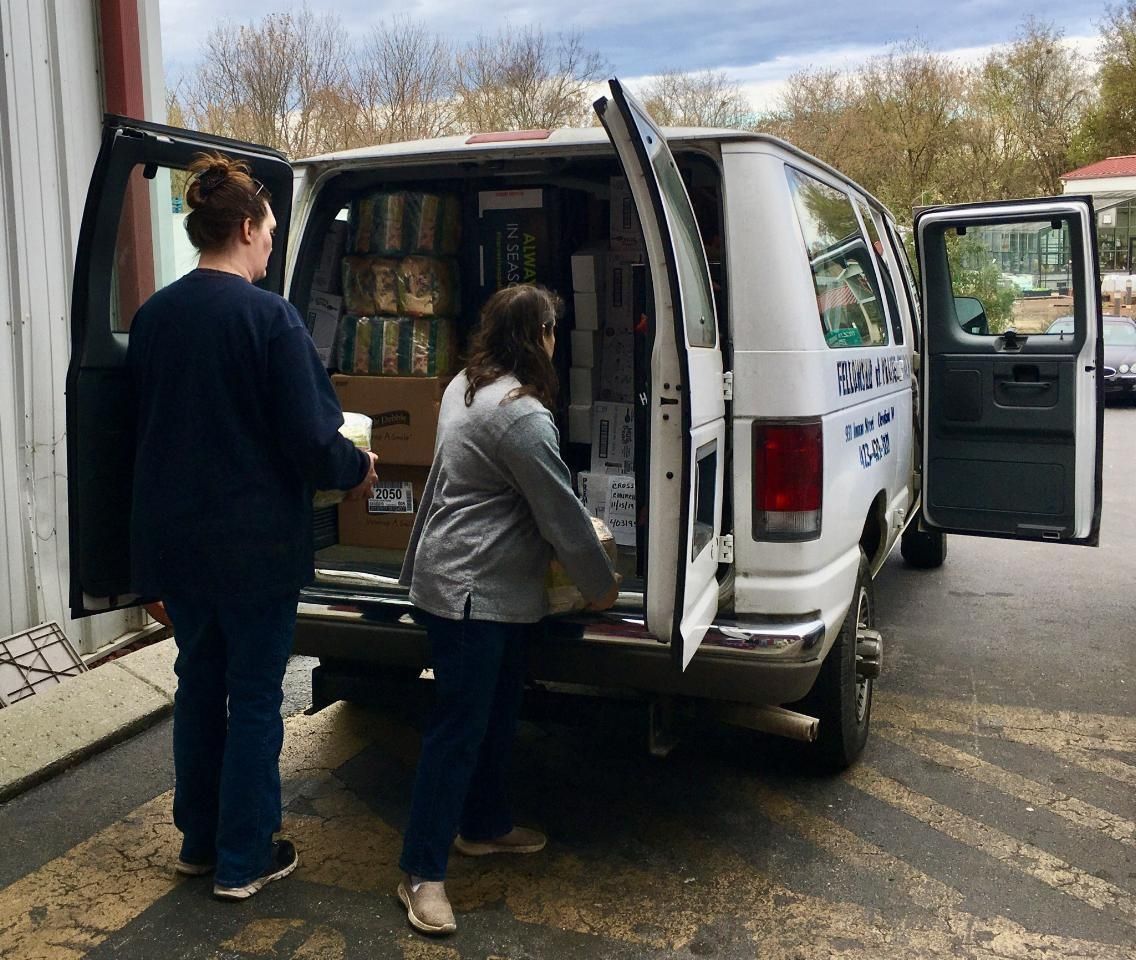 Two women are loading boxes into a white van.