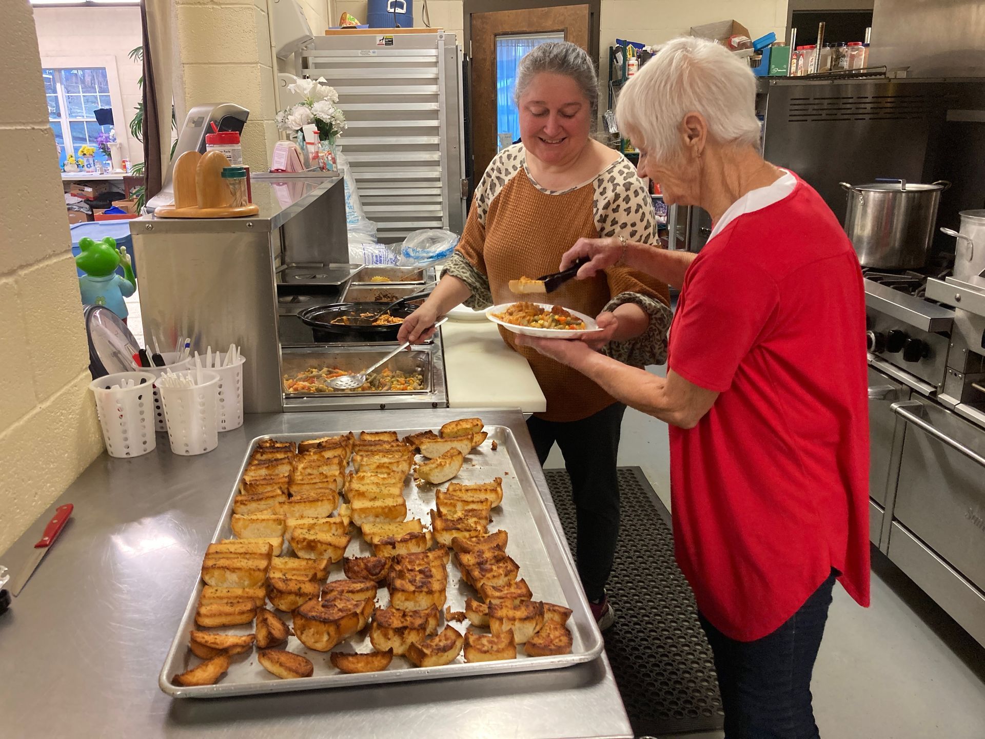 Two women are standing in a kitchen preparing food.