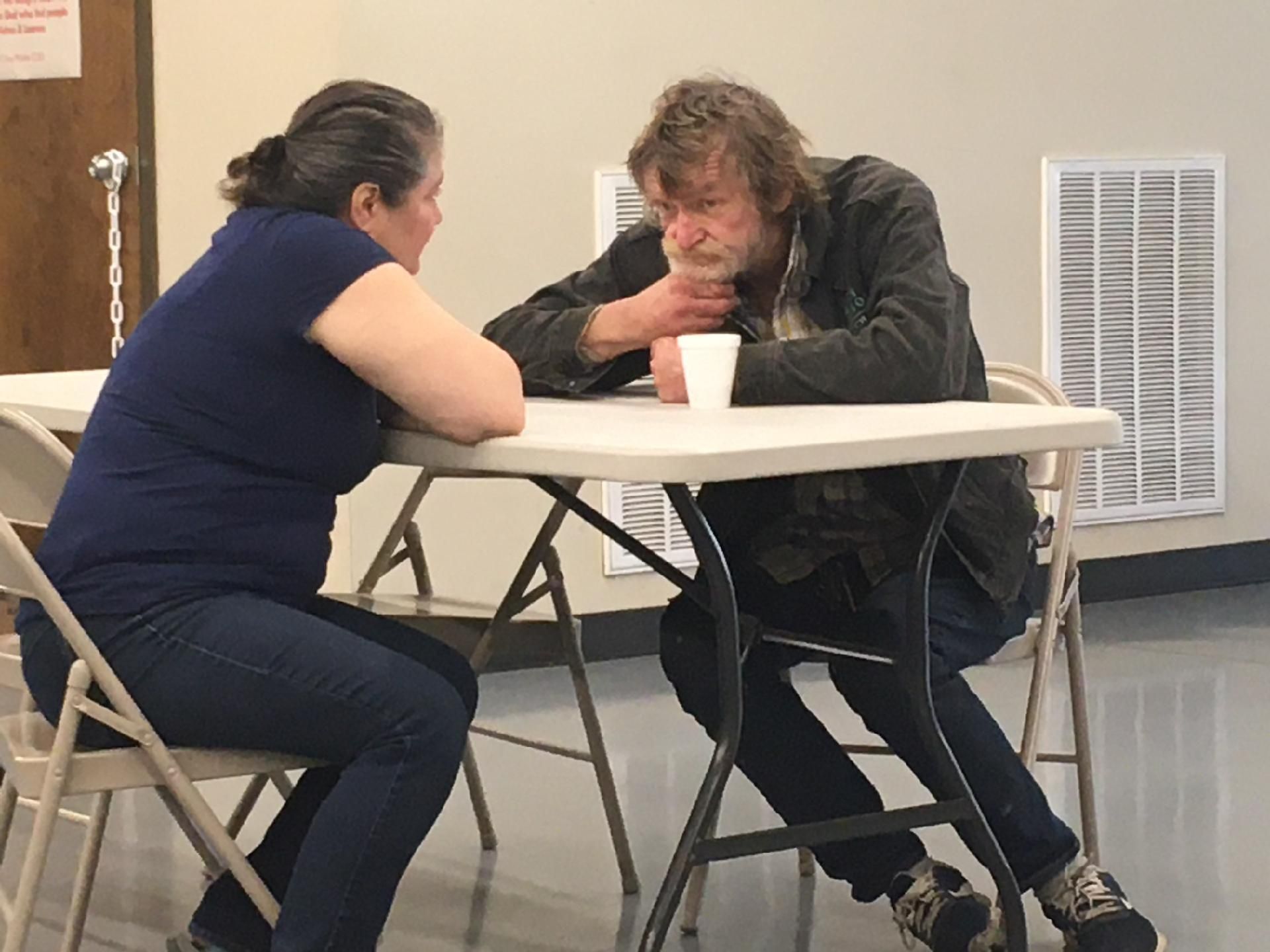 A man and a woman are sitting at a table talking to each other
