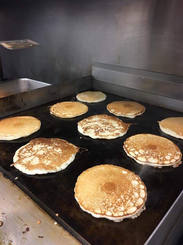 A bunch of pancakes are cooking on a grill.