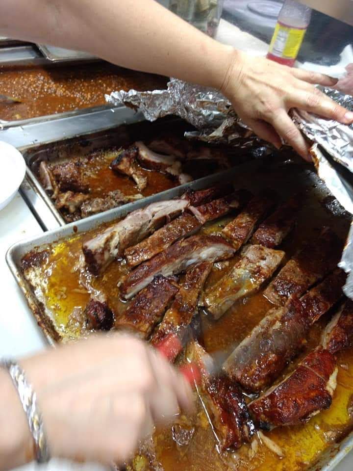 A person is cutting ribs in a pan with a fork.