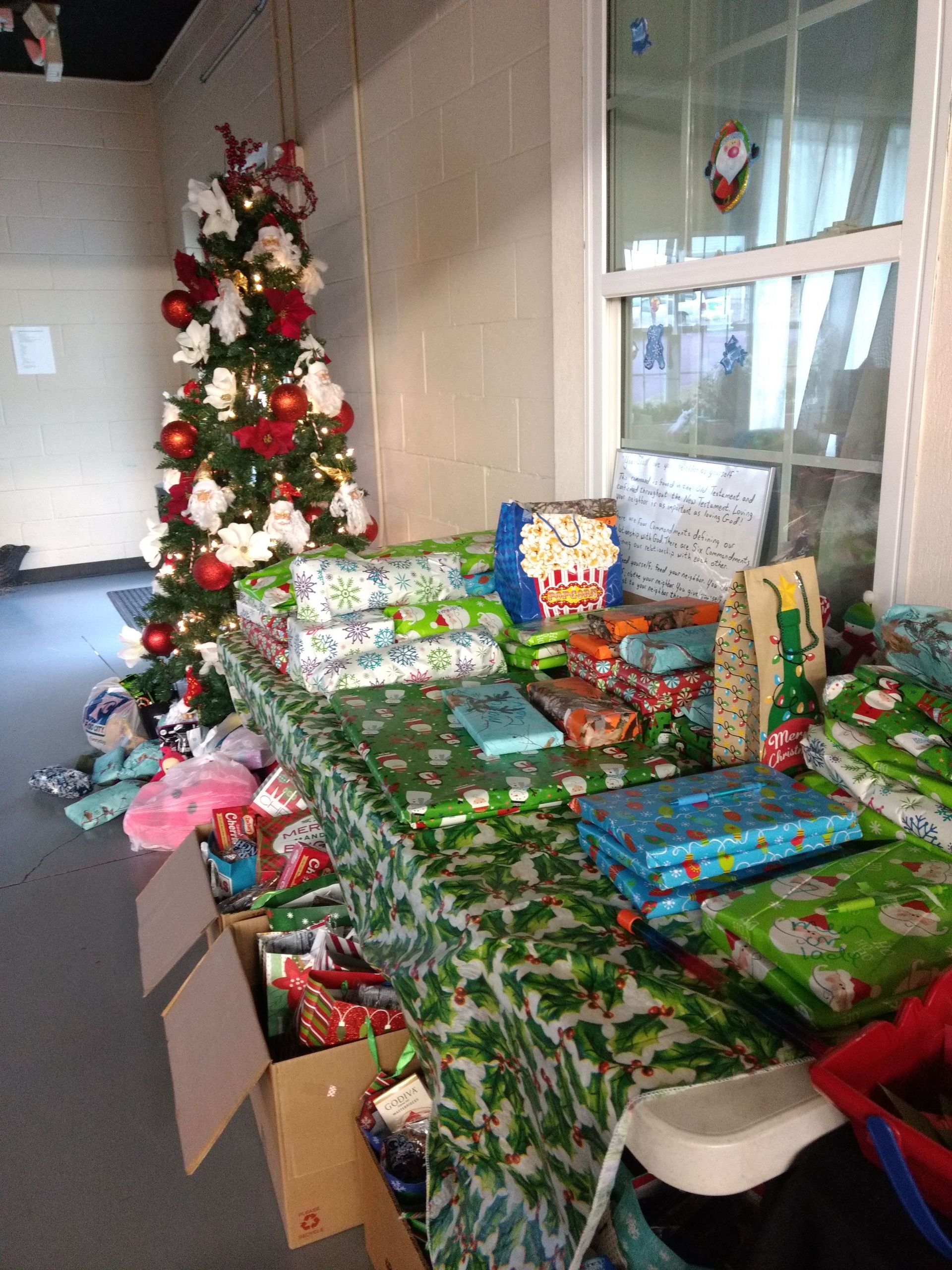 A christmas tree is behind a table full of presents