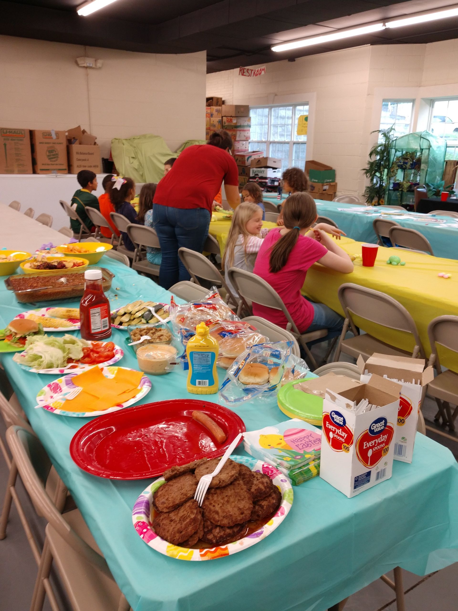 A group of children are sitting at tables with plates of food