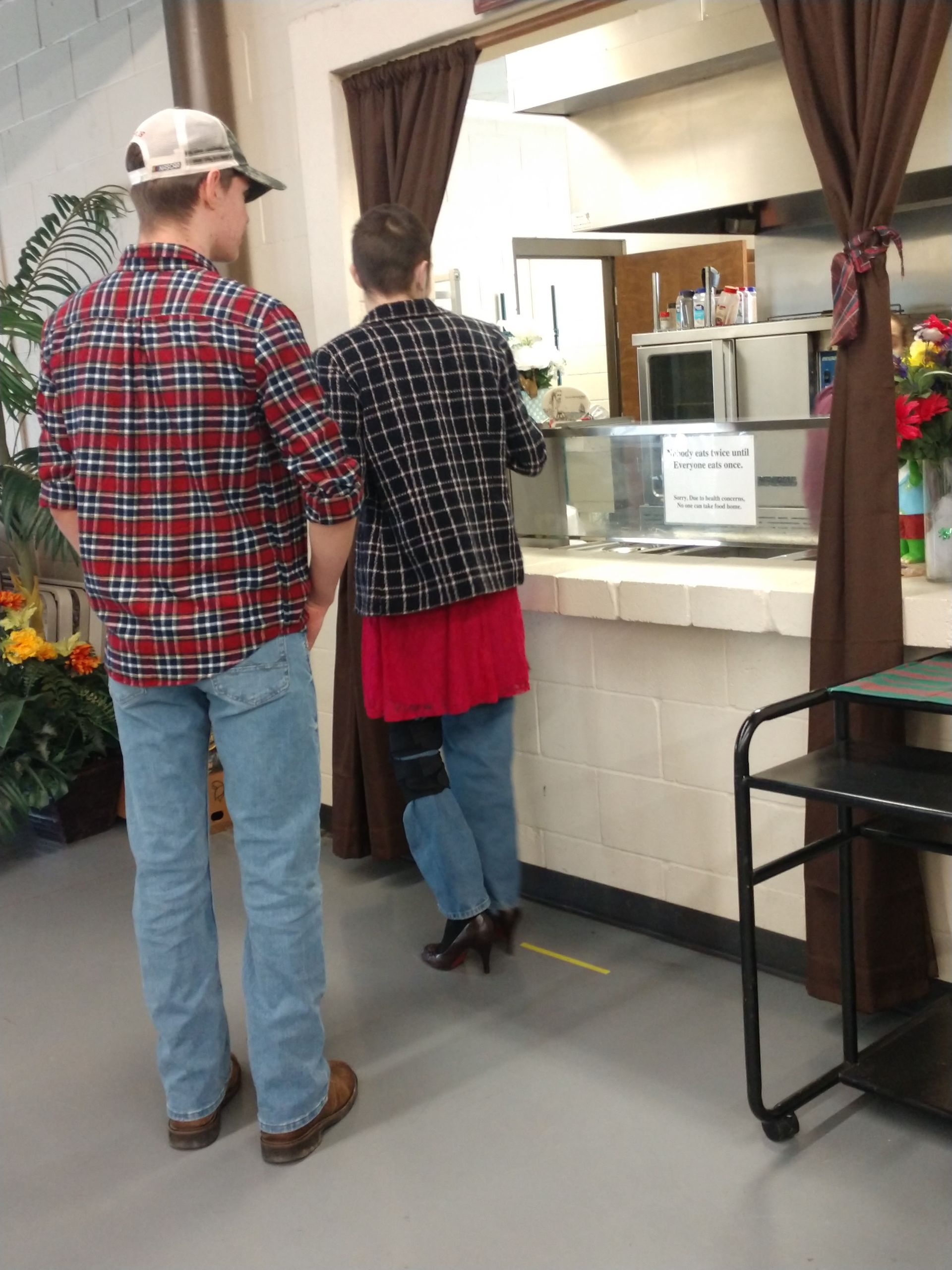 A man in a plaid shirt is standing next to a woman in a red skirt