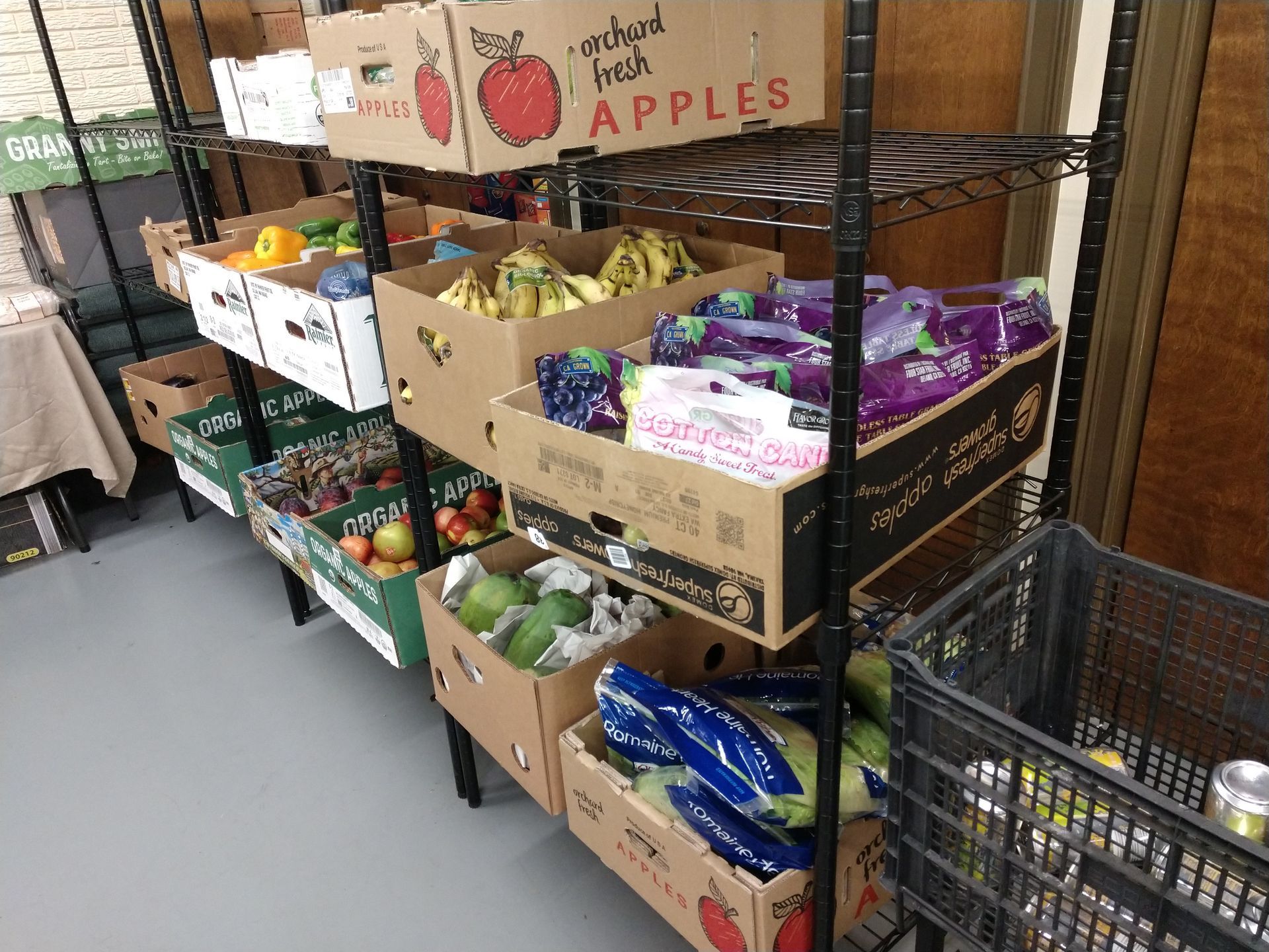 A shelf filled with boxes of fruit including apples and bananas.