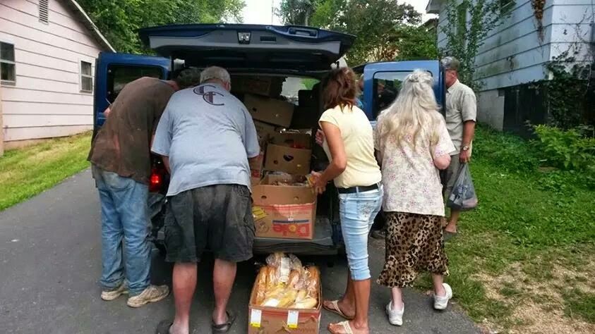 A group of people are loading groceries into the back of a van