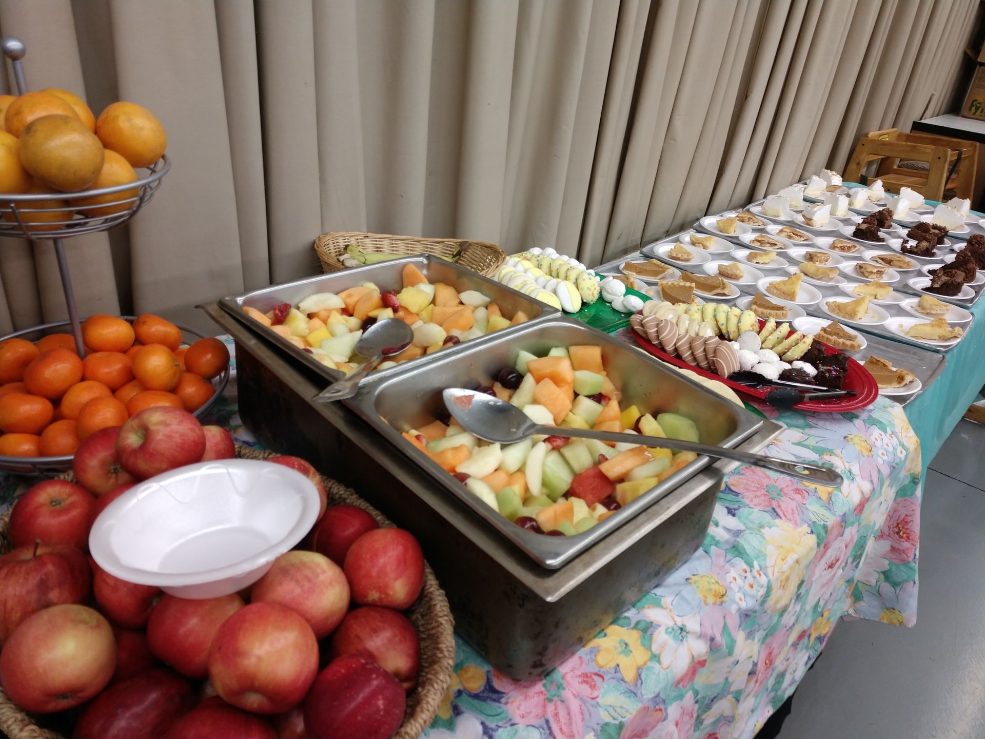 A buffet table with a variety of fruits and desserts