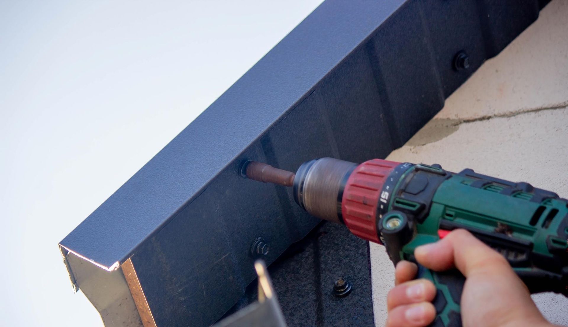 A person is using a drill to drill a hole in a wall.