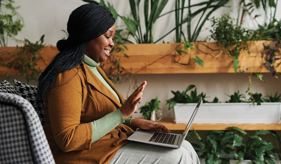 A woman is sitting on a couch using a laptop computer.