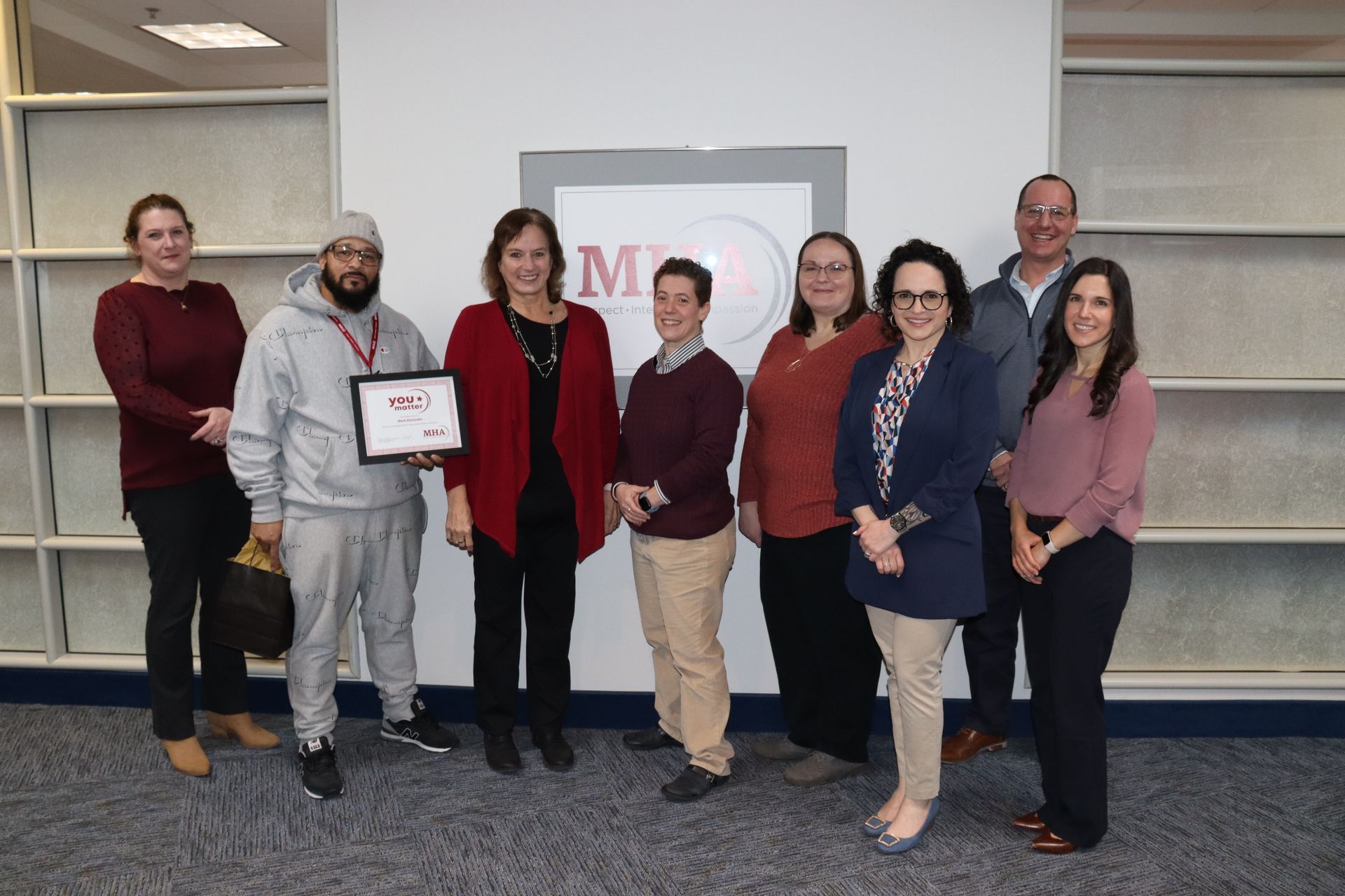 A group of people are posing for a picture in front of a wall.