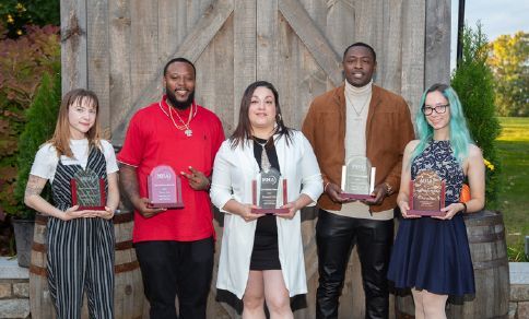 A group of people are standing next to each other holding awards.