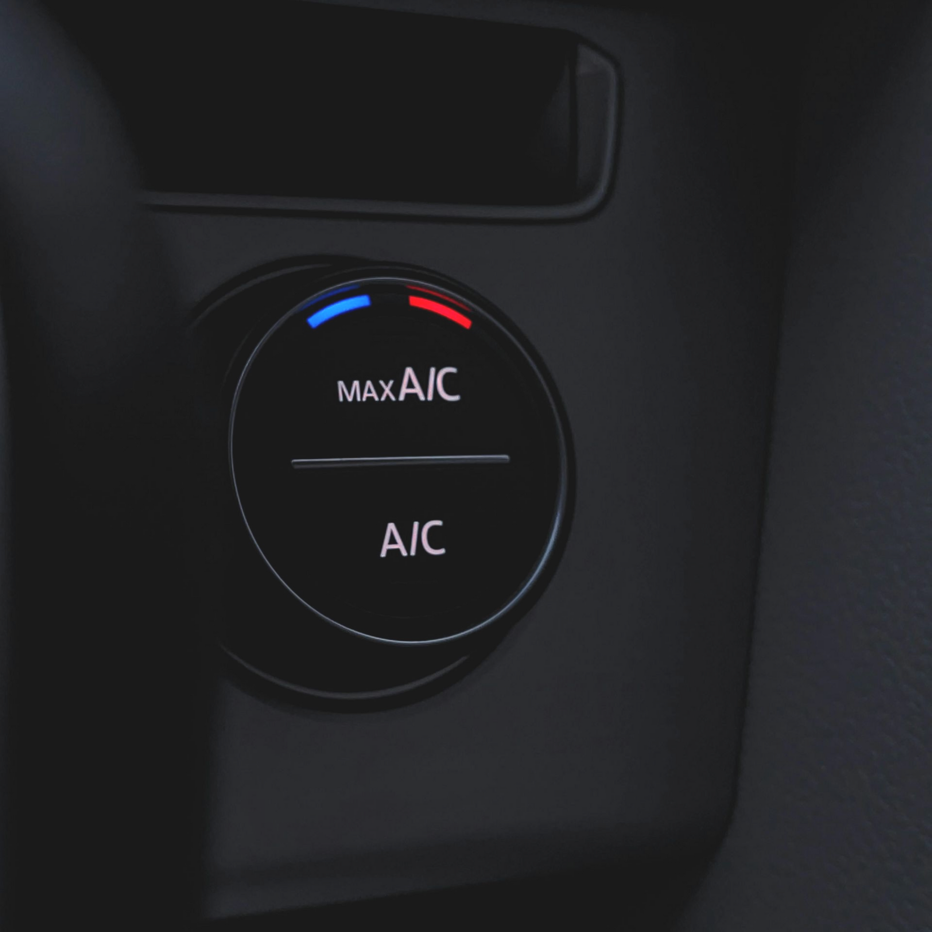 Car dashboard climate control knob labeled “Max A/C” and “A/C” with blue and red temperature markers