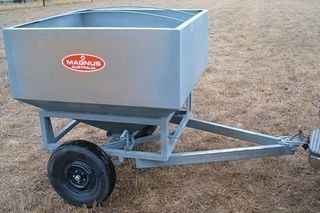 A small trailer is sitting on top of a dry grass field.
