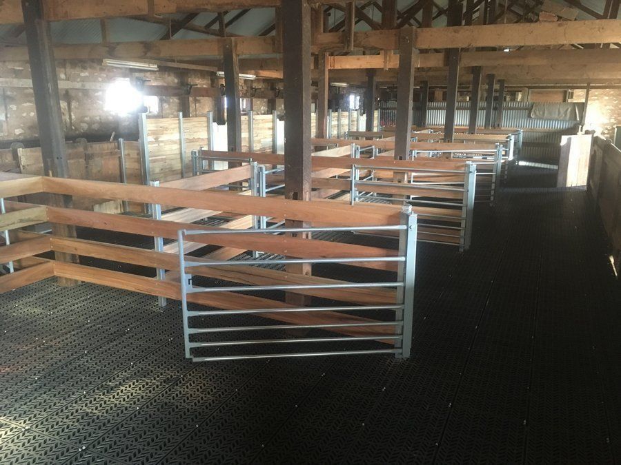 The inside of a barn with wooden fences and metal fences