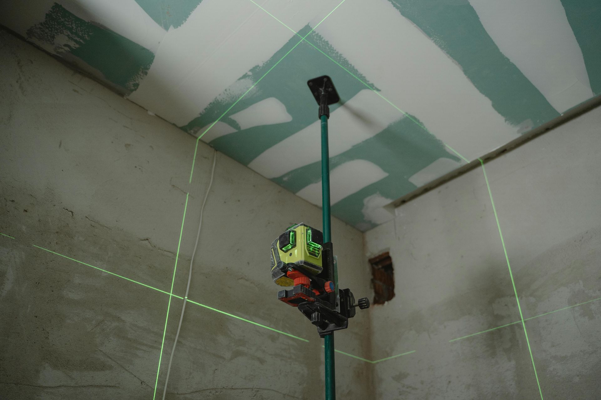 A person is using a laser level to measure the ceiling in a room.