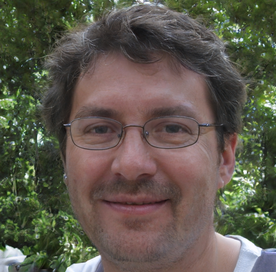 A man with glasses and a beard is smiling for the camera