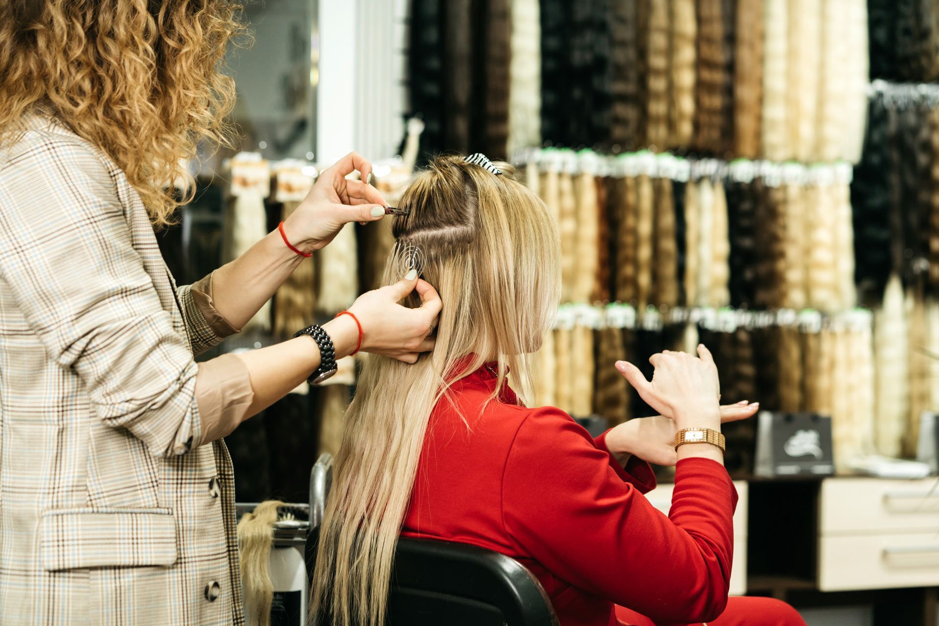 A woman is getting her hair done by a hairdresser in a salon.