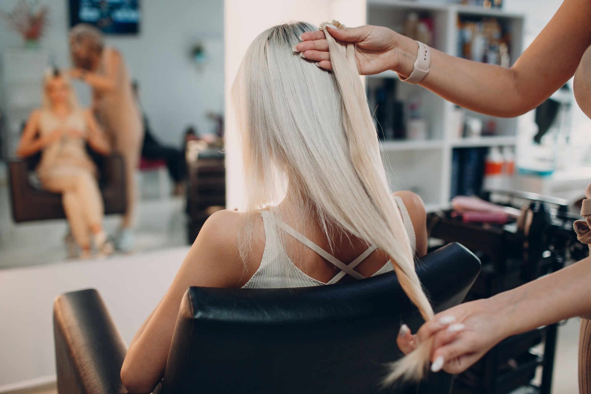 A woman is getting her hair done by a hairdresser in a salon.