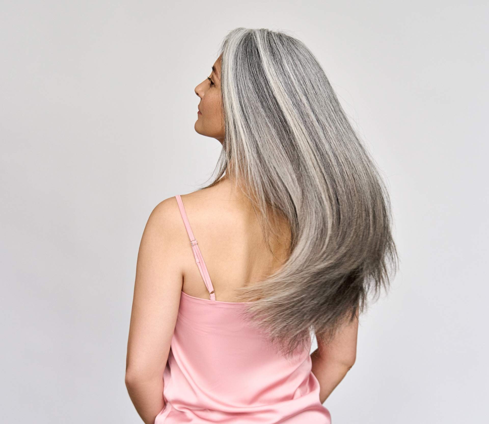 A woman with gray hair is wearing a pink tank top.