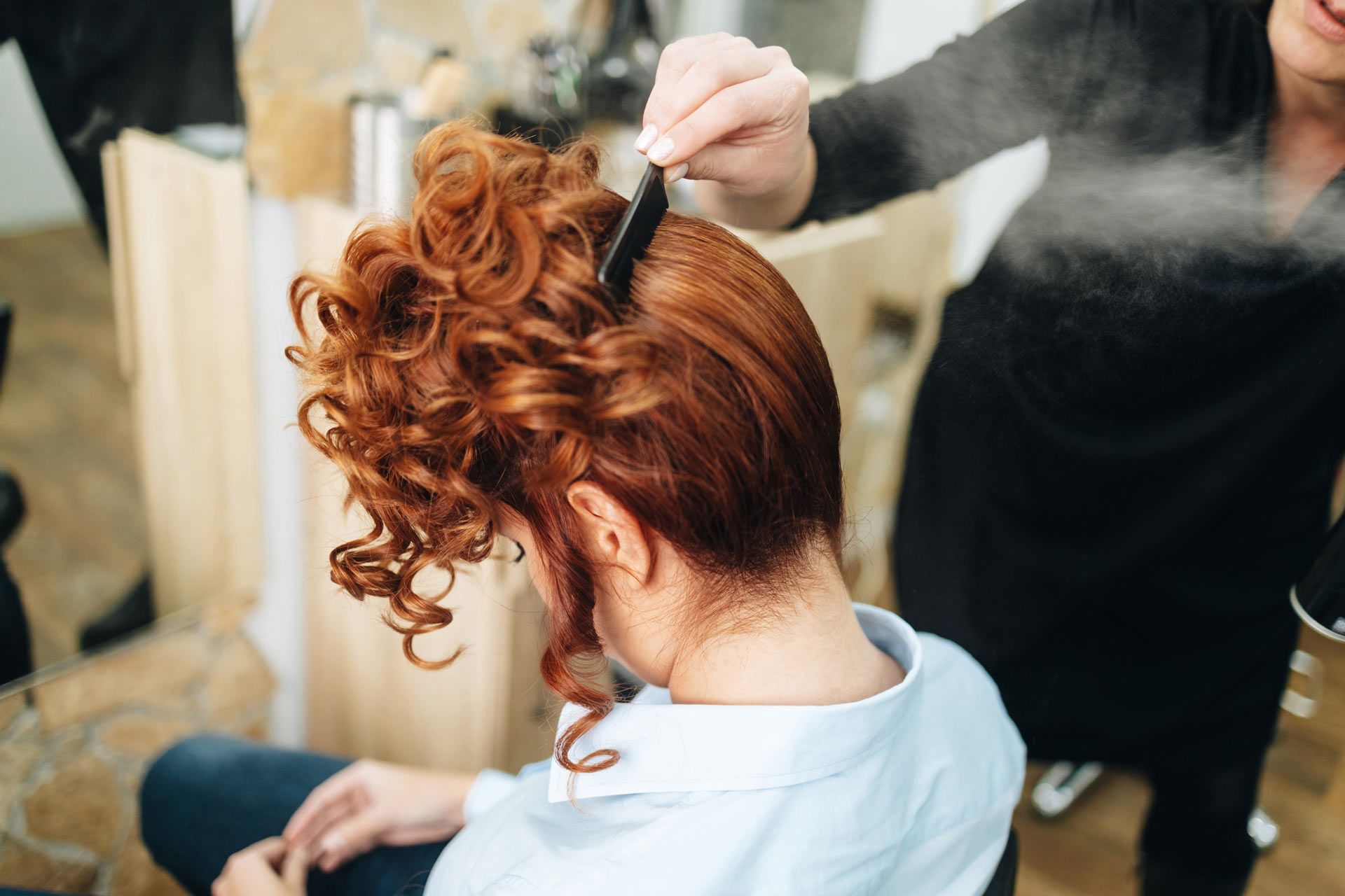 A woman is getting her hair done by a hairdresser in a salon.