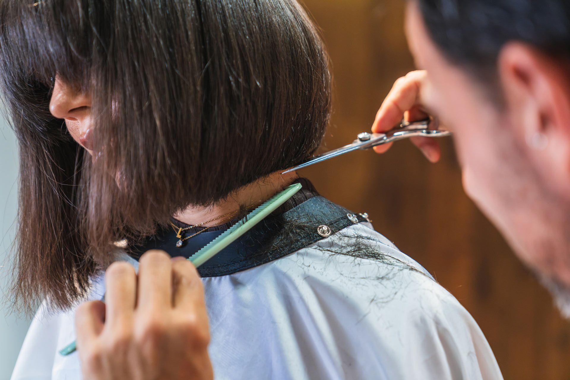 A woman is getting her hair cut by a hairdresser.