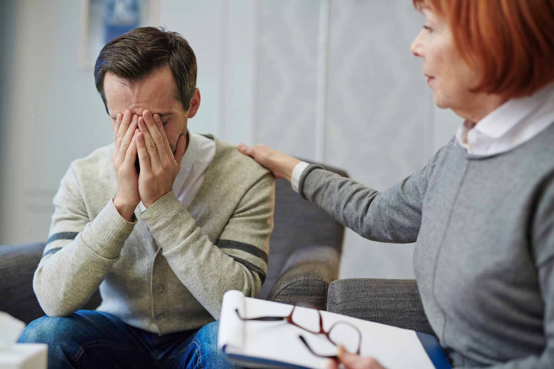 A woman is holding another woman 's hand while sitting in a chair.