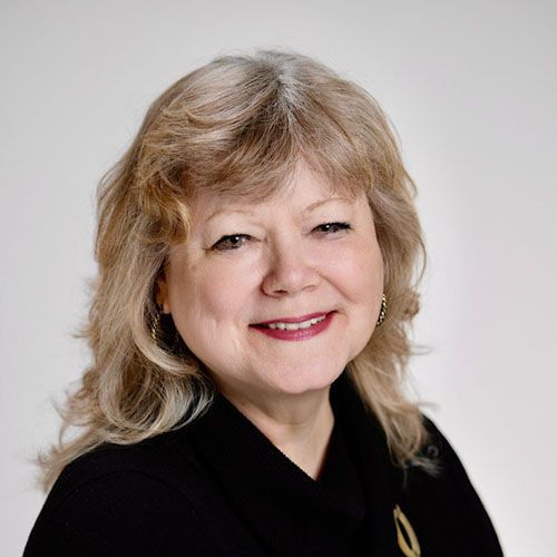 A woman wearing a black shirt and a necklace is smiling
