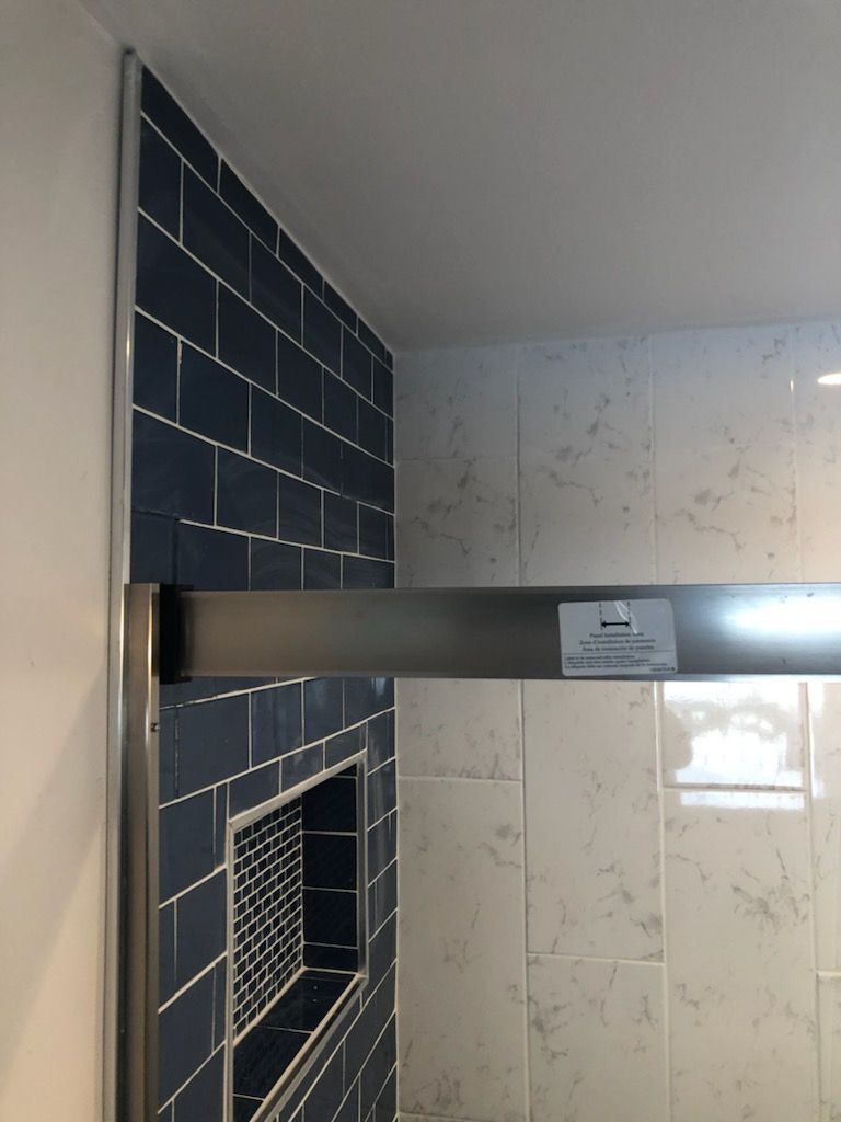 A bathroom with blue tiles and a stainless steel shower door